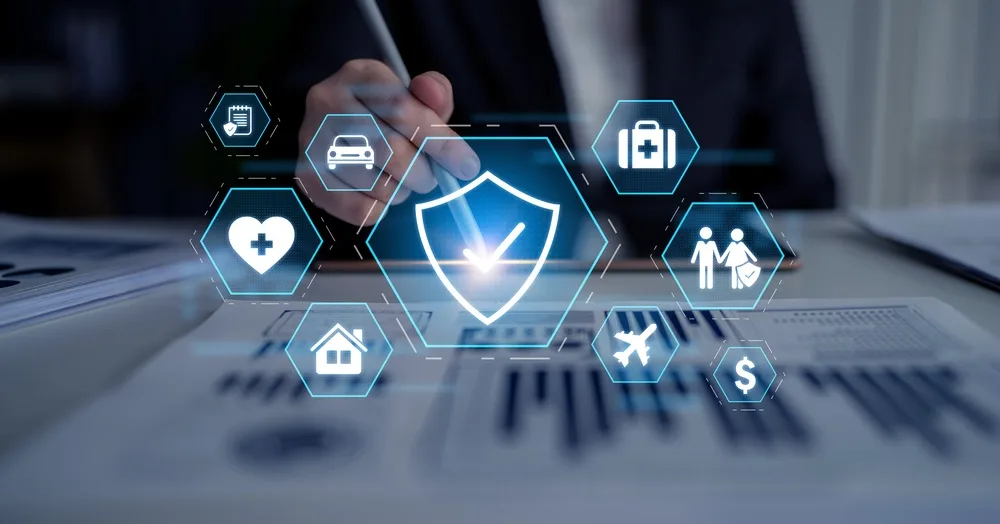 Hand with a stylus touching a shield icon, surrounded by insurance line icons: health, auto, home, travel, life and finance